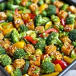 - 225 g Tempeh, in mundgerechte Würfel geschnitten - 2 Tassen Brokkoliröschen - 1 rote Paprika, in Scheiben geschnitten - 1 gelbe Paprika, in Scheiben geschnitten - 1 mittelgroße Zucchini, in Scheiben geschnitten - 3 Esslöffel Süß-Chili-Sauce Die Hauptzutaten machen das Gericht einfach und lecker. Tempeh bringt viel Protein und eine tolle Textur. Brokkoli und Paprika fügen Farbe und Vitamine hinzu. Die Zucchini sorgt für Frische und Leichtigkeit. - 2 Esslöffel Sojasauce - 1 Esslöffel Olivenöl - 1 Teelöffel Knoblauchpulver - 1 Teelöffel Ingwerpulver - Salz und Pfeffer nach Geschmack Gewürze und Öle geben dem Gericht Geschmack. Sojasauce sorgt für Umami. Olivenöl hilft beim Rösten und macht alles schön goldbraun. Knoblauchpulver und Ingwerpulver bringen Aroma. Salz und Pfeffer runden den Geschmack ab. - Sesam - Frühlingszwiebeln Die Garnierung macht das Gericht besonders. Sesam gibt einen nussigen Geschmack. Frühlingszwiebeln bringen Frische und Farbe. Zusammen verleihen sie dem Gericht eine ansprechende Optik. Heizen Sie zuerst den Ofen auf 200 °C vor. Dies stellt sicher, dass Ihr Gericht gleichmäßig gart. Legen Sie dann ein Backblech mit Backpapier aus. Das erleichtert die Reinigung und verhindert, dass das Essen anbrennt. Schneiden Sie 225 g Tempeh in mundgerechte Würfel. Das sorgt für eine schöne Textur beim Essen. Nehmen Sie dann 2 Tassen Brokkoliröschen, eine rote Paprika, eine gelbe Paprika und eine mittelgroße Zucchini. Schneiden Sie das Gemüse in gleichmäßige Stücke. So garen sie gleichmäßig und sehen toll aus. In einer kleinen Schüssel kombinieren Sie 3 Esslöffel Süß-Chili-Sauce, 2 Esslöffel Sojasauce und 1 Esslöffel Olivenöl. Fügen Sie 1 Teelöffel Knoblauchpulver und 1 Teelöffel Ingwerpulver hinzu. Vermischen Sie alles gut. Gießen Sie die Sauce über die Tempeh- und Gemüsemischung. Rühren Sie vorsichtig um, bis alles gleichmäßig bedeckt ist. Verteilen Sie die Mischung gleichmäßig auf dem Backblech. Stellen Sie sicher, dass alles eine Schicht bildet. Backen Sie das Gericht 25-30 Minuten lang. Wenden Sie die Mischung nach der Hälfte der Zeit. So wird der Tempeh goldbraun und das Gemüse zart. Nach dem Backen lassen Sie es kurz abkühlen. Dann garnieren Sie es mit Sesam und gehackten Frühlingszwiebeln. Um die beste Konsistenz zu erreichen, heize den Ofen auf 200 °C vor. Das ist wichtig, damit der Tempeh gut bräunt. Lege ein Backblech mit Backpapier aus. So bleibt alles schön kleberfrei. Backe das Gemüse und den Tempeh 25-30 Minuten. Wende die Mischung nach 15 Minuten. So wird alles gleichmäßig gar und goldbraun. Du kannst die Gewürze nach deinem Geschmack anpassen. Füge zum Beispiel etwas Paprikapulver hinzu. Das gibt dem Gericht mehr Tiefe. Möchtest du es schärfer? Verwende Chili-Flocken oder frische Chilis. So kannst du das Niveau der Schärfe gut steuern. Serviere das Gericht warm über Reis oder Quinoa. Diese Beilagen passen perfekt dazu. Richte die Mischung schön auf einem Teller an. Streue Sesam und gehackte Frühlingszwiebeln darüber. Das sieht nicht nur gut aus, sondern schmeckt auch frisch und knackig. {{image_4}} Für die Blechpfanne sind Gemüse sehr wichtig. Saisonales Gemüse macht das Gericht frisch und bunt. Im Frühling sind Spargel und Erbsen toll. Im Herbst passen Kürbis und Karotten gut. Du kannst auch Gemüse nach deinem Geschmack austauschen. Zucchini lässt sich leicht durch Aubergine ersetzen. Wenn du magst, füge auch grüne Bohnen oder Blumenkohl hinzu. Tempeh ist eine großartige Proteinquelle, aber du kannst auch Tofu verwenden. Tofu hat eine ähnliche Textur, ist aber milder im Geschmack. Wenn du Fleisch magst, probiere Hühnchen. Es passt gut zur Süß-Chili-Sauce. Für eine vegane Option kannst du auch Linsen oder Kichererbsen verwenden. Diese sind nahrhaft und fügen mehr Geschmack hinzu. Die Süß-Chili-Sauce gibt viel Geschmack, aber du kannst auch andere Saucen verwenden. Sojasauce, Teriyaki oder sogar Erdnusssauce sind gute Alternativen. Wenn du es knusprig magst, füge Nüsse oder Samen hinzu. Cashewkerne oder Mandeln passen gut zu dem Gericht. Sie geben zusätzlichen Crunch und machen das Essen noch besser. Um die Reste von Blechpfannen Süß-Chili Tempeh Gemüse gut zu lagern, gehe ich so vor: - Kühlschranklagerung: Fülle die Reste in einen luftdichten Behälter. So bleiben sie frisch. Stelle den Behälter in den Kühlschrank. - Haltbarkeit von Resten: Die Reste halten sich etwa 3 bis 4 Tage. Achte darauf, sie gut zu verschließen. Das Aufwärmen erfordert ein paar einfache Schritte, um die Qualität zu bewahren: - Beste Methoden zum Aufwärmen: Ich empfehle, die Reste im Ofen oder in der Pfanne zu erwärmen. So bleibt das Gemüse knackig. Stelle den Ofen auf 180 °C. Erwärme das Gemüse für etwa 10 bis 15 Minuten. - Tipps zur Vermeidung von matschigem Gemüse: Vermeide Mikrowellenwärmung, da sie das Gemüse weich macht. Füge beim Aufwärmen einen kleinen Spritzer Wasser hinzu, um das Austrocknen zu verhindern. Die Zubereitung dauert insgesamt 45 Minuten. Die Vorbereitungszeit beträgt etwa 15 Minuten. Das Backen im Ofen dauert 25 bis 30 Minuten. Sie können also schnell ein leckeres Gericht zaubern. Ja, Sie können das Gemüse und den Tempeh vorher vorbereiten. Schneiden Sie alles und stellen Sie es in den Kühlschrank. Mischen Sie die Sauce und bewahren Sie sie getrennt auf. So bleibt das Gemüse frisch. Am besten backen Sie das Gericht kurz vor dem Servieren. Ja, das Rezept kann glutenfrei sein. Verwenden Sie glutenfreie Sojasauce. Achten Sie darauf, dass alle anderen Zutaten ebenfalls glutenfrei sind. So genießen Sie das Gericht ohne Bedenken. Falls Sie kein Tempeh mögen, probieren Sie Tofu oder Hühnchen. Beide sind gute Proteinquellen. Sie können auch Kichererbsen für eine vegane Option verwenden. Jede dieser Alternativen passt gut zu den Aromen im Rezept. Dieses Rezept bietet viele leckere Möglichkeiten mit Tempeh und Gemüse. Du hast gelernt, wie man die Hauptzutaten auswählt und sie mit der richtigen Sauce mischt. Die Tipps helfen dir, die beste Konsistenz und den besten Geschmack zu erzielen. Denke auch daran, wie du die Reste richtig lagerst. Experimentiere mit Variationen, um neue Geschmacksrichtungen zu entdecken. Jede Zutat macht das Gericht besonders. Viel Spaß beim Kochen und Ausprobieren. Du wirst viele gesunde Mahlzeiten genießen!