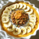Für unseren Kürbis-Pie Smoothie Bowl brauchen wir einige leckere und gesunde Zutaten. Du benötigst: - 1 Tasse Kürbispüree (aus der Dose oder frisch) - 1 gefrorene Banane - 1/2 Tasse griechischer Joghurt (oder pflanzlicher Joghurt) - 1/2 Tasse Mandelmilch (oder Milch nach Wahl) - 1 Esslöffel Ahornsirup (oder Honig) - 1/2 Teelöffel Vanilleextrakt - 1/2 Teelöffel Kürbiskuchengewürz Diese Zutaten machen die Basis für die Smoothie Schüssel. Das Kürbispüree gibt den perfekten herbstlichen Geschmack. Die gefrorene Banane sorgt für eine tolle Konsistenz und natürliche Süße. Der Joghurt fügt Cremigkeit hinzu, und die Mandelmilch macht alles fluffig. Um die Schüssel schön zu gestalten und den Geschmack zu verbessern, füge diese Toppings hinzu: - Granola - In Scheiben geschnittene Bananen - Chiasamen - Kürbiskerne - Ein Schuss Mandelbutter Diese Toppings bringen Textur und zusätzliche Nährstoffe. Granola gibt einen knusprigen Biss. Die Chiasamen sind reich an Ballaststoffen. Kürbiskerne verleihen einen nussigen Geschmack. Falls du pflanzliche Optionen bevorzugst, gibt es viele Möglichkeiten. Benutze einfach pflanzlichen Joghurt statt griechischem Joghurt. Mandelmilch kann durch Hafermilch oder Kokosmilch ersetzt werden. Ahornsirup kann mit Agavendicksaft oder Dattelsirup ersetzt werden. Diese Alternativen machen die Schüssel noch vielseitiger und für jeden geeignet. Um deinen Kürbis-Mix zu machen, nimm zuerst den Mixer. Füge 1 Tasse Kürbispüree hinzu. Du kannst Dosenpüree oder frisches verwenden. Gib dann die gefrorene Banane dazu. Sie macht den Mix süß und cremig. Füge 1/2 Tasse griechischen Joghurt hinzu. Das bringt einen tollen Geschmack. Jetzt kommt 1/2 Tasse Mandelmilch dazu. Du kannst auch andere Milchsorten nutzen. Dann gib 1 Esslöffel Ahornsirup oder Honig für die Süße hinzu. Füge 1/2 Teelöffel Vanilleextrakt und Kürbiskuchengewürz hinzu. Mixe alles auf hoher Stufe, bis die Mischung glatt ist. Wenn sie zu dick ist, füge mehr Mandelmilch hinzu. Achte darauf, die Wände des Mixers abzuschaben. So bleibt nichts zurück. Mixe die Zutaten gut, bis du eine cremige Konsistenz hast. Wenn du die Mischung nicht magst, kann ich dir raten, weniger Kürbiskuchengewürz zu verwenden. Du kannst auch mehr Banane oder Joghurt hinzufügen. Das macht die Mischung süßer oder cremiger. Experimentiere mit dem Mix, bis er dir gefällt. Gieße die fertige Mischung in eine große Schüssel. Jetzt kommt der spaßige Teil: die Toppings! Streue etwas Granola in die Mitte der Schüssel. Lege die in Scheiben geschnittenen Bananen gleichmäßig um die Mischung. Bestreue alles mit Chiasamen und Kürbiskernen. Für das letzte Extra träufle die Mandelbutter oben drauf. Jetzt hast du eine schöne, bunte Schüssel! Nimm einen Löffel und genieße die Aromen der Herbstzeit in jedem Bissen! Um den besten Geschmack zu erreichen, nutze frisches Kürbispüree. Es sorgt für mehr Aroma. Wenn du Dosen-Kürbis verwendest, achte darauf, dass es reines Püree ist. Die gefrorene Banane macht die Mischung cremig und kühl. Wenn der Smoothie zu dick ist, füge mehr Mandelmilch hinzu. Mixe alles gut, bis es eine glatte Konsistenz hat. So wird jeder Bissen lecker und einladend. Toppings machen deine Smoothie-Schüssel spannend. Probiere verschiedene Optionen aus. Granola gibt Crunch. In Scheiben geschnittene Bananen sind süß und frisch. Chiasamen sind gesund und nährstoffreich. Kürbiskerne bringen einen nussigen Geschmack. Mandelbutter fügt Cremigkeit hinzu. Du kannst auch Beeren oder Kokosraspel verwenden. Experimentiere mit verschiedenen Kombinationen für neue Geschmäcker. Frische Zutaten haben oft mehr Geschmack und Nährstoffe. Frische Bananen sind süßer und reicher an Vitaminen. Dosen-Zutaten sind praktisch und schnell. Achte darauf, dass sie keine Zusatzstoffe haben. Beide Optionen sind gut, aber frische Zutaten geben oft das beste Ergebnis. Überlege, was dir besser gefällt und was du gerade zur Hand hast. {{image_4}} Für eine vegane Variante, ersetze den griechischen Joghurt durch pflanzlichen Joghurt. Kokosjoghurt oder Sojajoghurt passen gut. Verwende auch pflanzliche Milch, wie Mandel- oder Hafermilch. Diese Optionen sind cremig und lecker. Der Geschmack bleibt fruchtig und voller Kürbisgewürz. Du bekommst dennoch die gleiche Gesundheit und den Genuss. Um mehr Protein hinzuzufügen, probiere Erdnussbutter oder Mandelbutter. Ein Esslöffel reicht schon. Auch Proteinpulver ist eine tolle Wahl. Wähle dein Lieblingspulver. Mixe es einfach mit den anderen Zutaten. So wird dein Smoothie Bowl noch nahrhafter. Diese Optionen machen ihn perfekt für Sportler oder aktive Menschen. Lass deiner Kreativität freien Lauf! Du kannst mit verschiedenen Gewürzen arbeiten. Zimt, Muskatnuss oder Ingwer geben neue Geschmäcker. Probiere auch Kakao für eine schokoladige Note. Ein Spritzer Zitronensaft bringt Frische. So wird dein Kürbis-Pie Smoothie Bowl immer wieder anders und spannend. Du wirst überrascht sein, wie viele Variationen du kreieren kannst! Wenn du nach dem Mixen noch etwas übrig hast, bewahre die Smoothie-Mischung in einem luftdichten Behälter auf. Stelle sicher, dass du ihn im Kühlschrank lagerst. So bleibt er frisch und lecker für bis zu zwei Tage. Vor dem Servieren solltest du die Mischung gut umrühren. So wird sie wieder cremig. Um die Smoothie-Mischung länger haltbar zu machen, kannst du sie einfrieren. Fülle die Mischung in Eiswürfelformen oder in einen gefrierfesten Behälter. Achte darauf, etwas Platz zu lassen, da die Mischung beim Gefrieren expandiert. Du kannst die gefrorenen Portionen später einfach in den Mixer geben. Mixe sie mit etwas frischer Milch oder Joghurt für einen schnellen Snack. Für die besten Ergebnisse ist es wichtig, die frischen Zutaten gut zu lagern. Bewahre Kürbispüree, Joghurt und Milch im Kühlschrank auf. Sie bleiben so länger frisch. Lagere Bananen bei Raumtemperatur, bis sie reif sind. Danach kannst du sie auch im Kühlschrank aufbewahren. Achte darauf, dass sie nicht zu lange liegen, um ihre besten Aromen zu erhalten. Ein Kürbis-Pie Smoothie Bowl ist sehr gesund. Kürbis ist reich an Vitaminen und Ballaststoffen. Er hat viel Vitamin A, das gut für die Augen ist. Die gefrorene Banane fügt Kalium hinzu. Kalium hilft, den Blutdruck zu regulieren. Griechischer Joghurt liefert Protein und Probiotika. Diese unterstützen die Verdauung. Mandelmilch ist eine gute, kalorienarme Wahl. Ahornsirup bietet natürliche Süße ohne raffinierten Zucker. Insgesamt ist diese Schüssel nahrhaft und lecker. Ja, du kannst die Banane weglassen. Sie sorgt für eine cremige Textur. Wenn du sie nicht magst, probiere Avocado oder eine andere gefrorene Frucht. Diese Optionen geben auch eine glatte Konsistenz. Du kannst auch mehr Joghurt hinzufügen, um die Textur zu verbessern. Denke daran, die Süße anzupassen. So bleibt dein Smoothie Bowl lecker. Die Smoothie-Schüssel schmeckt am besten frisch. Du kannst die Mischung jedoch bis zu zwei Tage im Kühlschrank lagern. Bewahre sie in einem luftdichten Behälter auf. Wenn du Toppings hinzufügst, mache das erst kurz vor dem Essen. So bleibt alles frisch und knusprig. Wenn du Reste hast, friere die Mischung ein. So kannst du sie später genießen. In diesem Blogbeitrag haben wir die wichtigen Zutaten für deinen Kürbis-Smoothie-Bowl und die besten Toppings besprochen. Ich habe dir Schritt-für-Schritt-Anleitungen gegeben. Zudem hast du Tipps zur Lagerung und viele Variationen entdeckt. Denk daran, Kreativität zählt! Ob frisch oder vegan, du kannst anpassen, was dir gefällt. Mach deinen Smoothie zu einem leckeren Erlebnis. Experimentiere und finde deinen perfekten Mix!