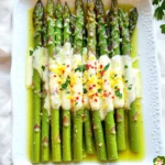 Für dieses leckere Rezept benötigst du folgende Hauptzutaten: - 450 g frischer Spargel, gewaschen und die Enden abgeschnitten - 30 ml Olivenöl - 5 g Knoblauchpulver - Abrieb von 1 Zitrone - 30 g frisch geriebener Parmesan - 5 ml frischer Zitronensaft - Salz und Pfeffer nach Geschmack - 1 g rote Pfefferflocken (optional) Diese Zutaten bringen Farbe und Geschmack auf dein Blech. Die Gewürze und Aromen sind entscheidend für den Geschmack: - Knoblauchpulver fügt einen feinen, herzhaften Geschmack hinzu. - Zitronenabrieb bringt Frische und Zitrusnoten in das Gericht. - Salz und Pfeffer verstärken die Aromen des Spargels. - Rote Pfefferflocken geben eine leichte Schärfe, wenn du das magst. Diese Gewürze machen den Spargel spannend und lecker. Die Garnitur macht das Gericht besonders: - Frische Petersilie, gehackt, bringt Farbe und Frische. - Nach dem Backen träufelst du frischen Zitronensaft darüber. - Der zusätzliche Parmesan sorgt für einen eleganten Look. Serviere den Spargel auf einer großen Platte. Das sieht toll aus und schmeckt noch besser! Zuerst heize deinen Ofen auf 220°C vor. Das sorgt für eine gleichmäßige Hitze. Wasche dann 450 g frischen Spargel gründlich und schneide die Enden ab. Es ist wichtig, dass der Spargel frisch ist, um den besten Geschmack zu erzielen. In einer großen Schüssel vermenge den Spargel mit 30 ml Olivenöl. Füge 5 g Knoblauchpulver, den Abrieb von einer Zitrone, Salz und Pfeffer nach Geschmack hinzu. Wenn du es etwas schärfer magst, kannst du auch rote Pfefferflocken verwenden. Mische alles gut, bis der Spargel schön überzogen ist. Verteile den gewürzten Spargel gleichmäßig auf einem Backblech. Achte darauf, dass er in einer einzigen Schicht liegt. So garen die Stangen gleichmäßig und werden schön zart. Jetzt kommt der besondere Teil: Streue 30 g frisch geriebenen Parmesan gleichmäßig über den Spargel. Dieser Käse wird beim Backen schmelzen und dem Spargel einen tollen Geschmack geben. Schiebe das Backblech in den vorgeheizten Ofen und backe den Spargel für 10-12 Minuten. Der Spargel sollte zart sein und der Käse leicht goldbraun. Nach dem Backen nimmst du das Blech heraus und träufelst 5 ml frischen Zitronensaft über den Spargel. Dies bringt eine frische Note. Vor dem Servieren kannst du ihn mit frisch gehackter Petersilie garnieren. Serviere den Spargel auf einer großen Platte und genieße die leckeren Aromen! Um den Spargel perfekt zu backen, heizen Sie Ihren Ofen auf 220°C vor. Vergewissern Sie sich, dass der Spargel gleichmäßig mit Olivenöl und Gewürzen bedeckt ist. Legen Sie ihn in einer einzigen Schicht auf das Backblech. So wird er gleichmäßig gar. Backen Sie den Spargel 10-12 Minuten. Er sollte zart sein und der Käse goldbraun. Ein häufiger Fehler ist, den Spargel zu überladen. Wenn Sie zu viel auf dem Blech haben, gart er ungleichmäßig. Ein weiterer Fehler ist, den Spargel nicht zu würzen. Salz und Pfeffer sind wichtig für den Geschmack. Vermeiden Sie auch, den Zitronensaft vor dem Backen hinzuzufügen. Er sollte erst nach dem Backen draufkommen, um den frischen Geschmack zu bewahren. Servieren Sie den Spargel auf einer großen Platte. Träufeln Sie etwas übrig gebliebenen Zitronensaft darüber. Zum Garnieren können Sie frisch gehackte Petersilie verwenden. Für zusätzlichen Geschmack, streuen Sie mehr Parmesan darüber. Dieser Spargel passt gut zu Fisch oder Huhn. Er kann auch eine tolle Beilage zu Pasta sein. {{image_4}} Wenn du gerne experimentierst, gibt es viele Wege, um das Rezept zu variieren. Statt Spargel kannst du Brokkoli oder Zucchini verwenden. Beide Gemüse passen gut zu den Aromen. Du kannst auch Parmesan durch Pecorino ersetzen, um einen salzigeren Geschmack zu bekommen. Für eine glutenfreie Option, achte darauf, dass alle Zutaten glutenfrei sind. Du kannst den Spargel als Beilage zu vielen Gerichten servieren. Er passt gut zu gebratenem Hähnchen oder Lachs. Auch zu Pasta ist der Spargel eine tolle Ergänzung. Koche einfach die Pasta und füge den gebackenen Spargel hinzu. Ein Spritzer Zitronensaft macht es frisch und lecker. Für vegane Variationen kannst du den Parmesan durch Hefeflocken ersetzen. Sie geben einen ähnlichen Geschmack ohne Milchprodukte. Wenn du auf Kohlenhydrate achtest, ist der Spargel eine großartige Wahl. Er hat wenig Kalorien und viele Nährstoffe. Achte darauf, die Gewürze nach deinem Geschmack anzupassen. Wenn du Reste von deinem Spargelgericht hast, lege sie in einen luftdichten Behälter. So bleiben sie frisch. Stelle den Behälter in den Kühlschrank. So kannst du die Aromen länger genießen. Achte darauf, dass der Spargel gut abgekühlt ist, bevor du ihn verpackst. Das verhindert Feuchtigkeit, die die Textur ruinieren könnte. Um den Spargel wieder aufzuwärmen, lege ihn auf ein Backblech. Heize deinen Ofen auf 180°C vor. Backe ihn für etwa 5-7 Minuten. So bleibt der Spargel knackig und der Käse schmilzt schön. Du kannst den Spargel auch in der Mikrowelle aufwärmen. Stelle die Mikrowelle auf niedrige Leistung und erwärme ihn für 1-2 Minuten. Im Kühlschrank hält sich der Spargel 3 bis 4 Tage. Wenn du ihn länger aufbewahren möchtest, friere ihn ein. Er bleibt im Gefrierfach bis zu 3 Monate frisch. Stelle sicher, dass du ihn in einem gefrierfesten Behälter oder Beutel verpackst. Füge das Datum hinzu, um die Frische im Blick zu behalten. Ja, du kannst gefrorenen Spargel verwenden. Achte darauf, ihn vorher aufzutauen. Drücke das Wasser gut aus, bevor du mit dem Rezept beginnst. Gefrorener Spargel hat oft eine weichere Textur. Du musst die Backzeit eventuell anpassen. Um den besten Geschmack zu erzielen, verwende frischen Spargel. Der Geschmack ist intensiver und knackiger. Füge Olivenöl, Knoblauchpulver und Zitronenschale hinzu. Diese Aromen heben den Spargel hervor. Du kannst auch frische Kräuter wie Petersilie verwenden. Sie bringen Frische und Farbe in das Gericht. Dieses Gericht passt gut zu vielen Hauptspeisen. Serviere es mit gegrilltem Hähnchen oder Fisch. Es ergänzt auch Pasta-Gerichte perfekt. Für eine vegetarische Option, kombiniere es mit Quinoa oder Risotto. Die Kombinationen sind nahezu unbegrenzt und machen deine Mahlzeit besonders lecker. In diesem Blogbeitrag haben wir die wichtigsten Zutaten und Zubereitungsschritte für ein Spargelrezept besprochen. Wir haben auch Tipps gegeben, wie du Fehler vermeidest und das Gericht perfekt backst. Verschiedene Variationen und Servierideen helfen, es an deinen Geschmack anzupassen. Zum Schluss haben wir Lagerung und Haltbarkeit der Reste behandelt. Du kannst jetzt mit frischem Spargel kreativ sein und verschiedene leckere Optionen ausprobieren. Nutze deine neuen Kenntnisse, um dein Gericht zu perfektionieren und deinen Gästen zu imponieren!