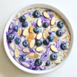 - 1 Tasse Haferflocken (großflockig) - 1 Tasse Mandelmilch (oder eine andere pflanzliche Milchalternative) - 1/2 Tasse griechischer Joghurt (oder eine milchfreie Alternative) Die Hauptzutaten sind der Schlüssel zu einem großartigen Geschmack. Haferflocken sind voll von Ballaststoffen. Sie halten uns lange satt. Mandelmilch gibt dem Gericht eine sanfte Süße. Griechischer Joghurt fügt Cremigkeit hinzu und macht es nahrhaft. - 1 Tasse frische Blaubeeren (plus extra zum Garnieren) - 1/4 Tasse Mandelbutter - 2 Esslöffel Ahornsirup (oder Honig) Zusätzliche Zutaten bringen mehr Geschmack. Frische Blaubeeren sind süß und lecker. Sie sind auch gesund und reich an Antioxidantien. Mandelbutter fügt einen nussigen Geschmack hinzu. Ahornsirup gibt eine feine Süße und ist ein toller natürlicher Süßstoff. - 1/2 Teelöffel Vanilleextrakt - 1 Esslöffel Chiasamen - Eine Prise Salz Gewürze und Extras machen das Gericht besonders. Vanilleextrakt verstärkt den Geschmack der Blaubeeren. Chiasamen sind eine tolle Quelle für Omega-3-Fettsäuren. Eine Prise Salz hebt die Aromen hervor und rundet den Geschmack ab. Zuerst nimmst du eine große Rührschüssel. Dort kommen die Haferflocken hinein. Füge die Mandelmilch hinzu, um die Haferflocken gut zu hydratisieren. Jetzt ist der griechische Joghurt dran. Dieser macht die Mischung cremig und lecker. Ein Spritzer Vanilleextrakt bringt einen feinen Geschmack. Jetzt rührst du alles gut durch. Achte darauf, dass sich die Zutaten gleichmäßig vermischen. Nun geben wir die Mandelbutter dazu. Diese sorgt für einen nussigen Geschmack und eine cremige Textur. Füge auch den Ahornsirup hinzu, um etwas Süße zu bekommen. Dann kommen die Chiasamen und eine Prise Salz dazu. Rühre alles erneut gut um. Jetzt ist es Zeit für die Blaubeeren. Hebe sie vorsichtig unter die Mischung, damit sie ganz bleiben. Teile die fertige Mischung gleichmäßig auf zwei Gläser oder Schalen auf. Decke die Gefäße gut ab. Stelle sie über Nacht in den Kühlschrank. So können die Haferflocken die Aromen aufnehmen. Am nächsten Tag rührst du die Mischung gut durch. Falls sie zu dick ist, gib einen Spritzer Mandelmilch hinzu. Garniere dein Gericht mit frischen Blaubeeren und geschmorten Mandeln. Jetzt ist dein Frühstück bereit! Um die perfekte Konsistenz der Blaubeer Mandel Übernacht Haferflocken zu erreichen, kannst du die Flüssigkeit anpassen. Möchtest du es dünnflüssiger? Füge einfach mehr Mandelmilch hinzu. Für eine dickere Variante lasse die Mischung länger im Kühlschrank. Die Wahl der Milch ist ebenfalls wichtig. Mandelmilch ist eine tolle Option, aber du kannst auch Hafermilch oder Sojamilch verwenden. Achte darauf, die Pflanzenmilch gut zu wählen, um den Geschmack zu verbessern. Wenn du die Aromen variieren möchtest, gibt es viele Möglichkeiten. Mandelbutter ist lecker, aber Erdnussbutter oder Cashewbutter sind auch großartige Alternativen. Süßungsmittel sind ebenfalls anpassbar. Du kannst Agavendicksaft, Honig oder Kokosblütenzucker verwenden. Experimentiere mit verschiedenen Süßungsmitteln, um deinen perfekten Geschmack zu finden. Die Kombinationen für Toppings sind endlos. Du kannst gehackte Nüsse, frische Früchte oder sogar Joghurt hinzufügen. Diese Toppings bringen zusätzlichen Geschmack und Textur. Du kannst die Haferflocken kalt oder warm genießen. Wenn du sie warm magst, wärme sie in der Mikrowelle für ein paar Sekunden auf. So hast du ein leckeres Frühstück, das dich den ganzen Tag über sättigt. {{image_4}} Du kannst die Blaubeeren durch Himbeeren oder Erdbeeren ersetzen. Diese Beeren geben einen tollen Geschmack. Wenn du einen süßeren Touch magst, füge Trockenfrüchte wie Rosinen oder Datteln hinzu. Diese bringen eine angenehme Süße und zusätzliche Nährstoffe. Probiere verschiedene Nussbutter, um neue Aromen zu entdecken. Erdnussbutter oder Cashewbutter sind großartige Alternativen. Nüsse wie Mandeln oder Walnüsse als Topping machen dein Frühstück noch besser. Sie geben Crunch und gesunde Fette. Du kannst glutenfreie Haferflocken verwenden, wenn du glutenfrei leben möchtest. Achte auf die richtige Marke, um sicher zu sein. Für die Milch gibt es viele Alternativen. Sojamilch oder Kokosmilch sind gute Optionen. Diese halten das Rezept lecker und nahrhaft. Die Blaubeer Mandel Übernacht Haferflocken halten sich bis zu 5 Tage im Kühlschrank. Lagern Sie sie in einem luftdichten Behälter. So bleiben sie frisch und lecker. Wenn Sie die Mischung länger aufbewahren möchten, können Sie die Haferflocken auch einfrieren. Füllen Sie die Mischung in gefrierfeste Behälter. Sie können sie bis zu 3 Monate einfrieren. Lassen Sie sie dann einfach im Kühlschrank auftauen. Um die Haferflocken zu erwärmen, verwenden Sie die Mikrowelle. Stellen Sie die Leistung auf mittel und erhitzen Sie sie 1 bis 2 Minuten lang. Überprüfen Sie die Temperatur. Wenn sie zu dick sind, fügen Sie einen Spritzer Mandelmilch hinzu. Sie können die Haferflocken auch auf dem Herd erwärmen. Geben Sie sie in einen kleinen Topf und erhitzen Sie sie bei niedriger Hitze. Rühren Sie häufig um, damit sie nicht anbrennen. Bereiten Sie die Haferflocken für die Woche vor. Teilen Sie die Mischung in Gläser oder kleine Schalen auf. So sind sie schnell und einfach griffbereit. Eine Portion reicht für ein Frühstück oder einen Snack. Wenn Sie mehr Variationen wünschen, können Sie verschiedene Früchte oder Nüsse hinzufügen. Lagern Sie die Portionen im Kühlschrank. So bleibt alles frisch und lecker. - Die Übernacht-Haferflocken sind im Kühlschrank bis zu 4 Tage haltbar. - Achte darauf, sie in einem gut verschlossenen Behälter zu lagern. - So bleiben sie frisch und lecker. - Ja, du kannst das Rezept leicht veganisieren. - Ersetze den griechischen Joghurt durch pflanzlichen Joghurt. - Verwende Mandelmilch oder eine andere pflanzliche Milchalternative. - Achte darauf, dass der Ahornsirup oder Honig vegan ist. - Haferflocken sind eine tolle Quelle für Ballaststoffe. - Sie helfen, den Blutzucker zu regulieren. - Sie fördern ein langanhaltendes Sättigungsgefühl. - Hafer enthält wichtige Vitamine und Mineralstoffe. - Diese Nährstoffe unterstützen die Gesundheit des Herzens. Diese Anleitung hilft dir, köstliche Übernacht-Haferflocken zu machen. Mit einfachen Hauptzutaten wie Haferflocken, Mandelmilch und Joghurt entsteht ein nahrhaftes Frühstück. Du kannst frische Blaubeeren, Mandelbutter und Gewürze hinzufügen, um den Geschmack zu verbessern. Experimentiere mit Variationen und anderen Zutaten für neue Aromen. Denke daran, die Mischung im Kühlschrank gut zu lagern. So bleibt alles frisch. Probier es aus und genieße ein gesundes Frühstück, das dir Energie gibt.